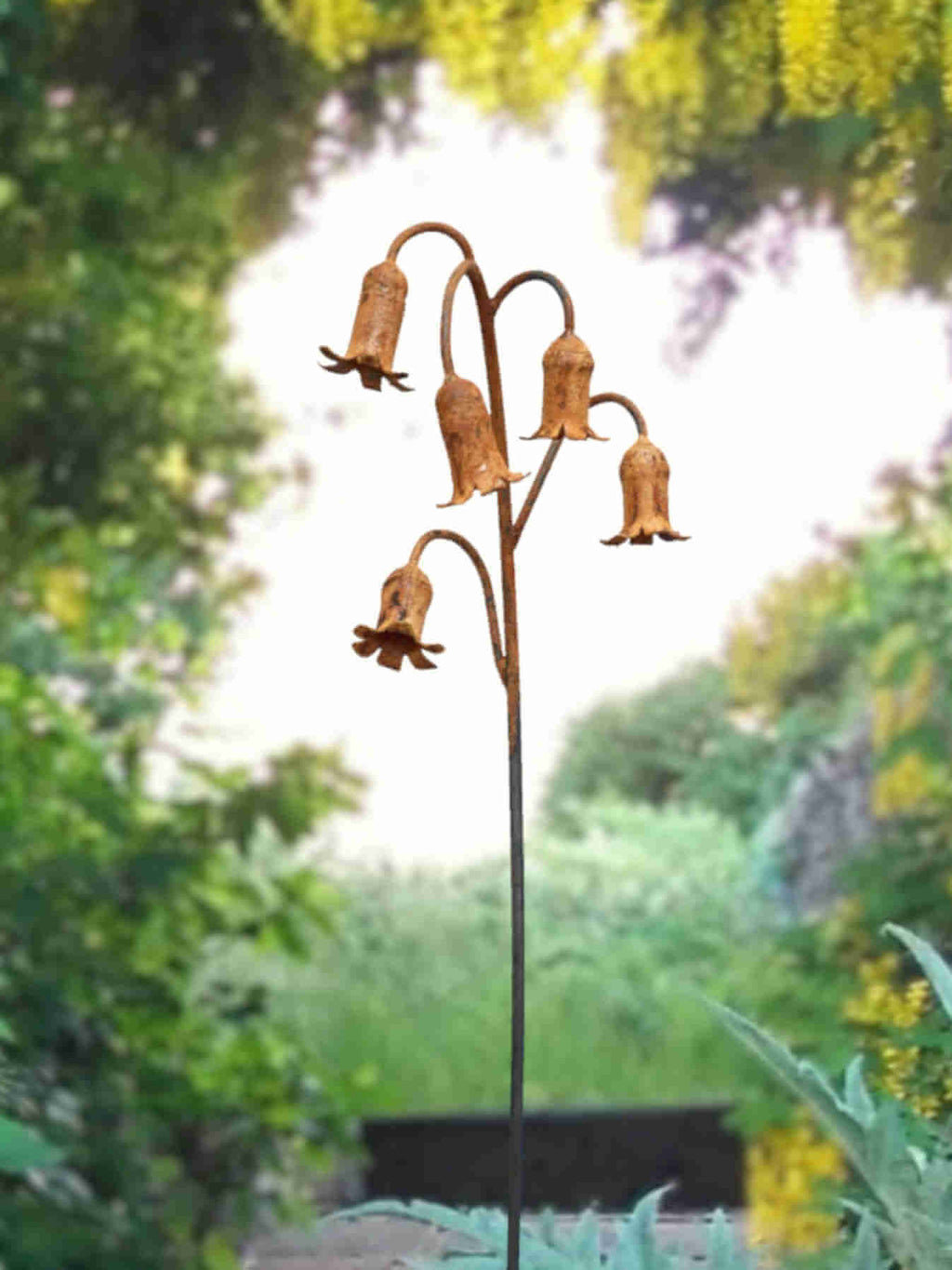Rusty metal Bluebells sculpture under a laburnum arch