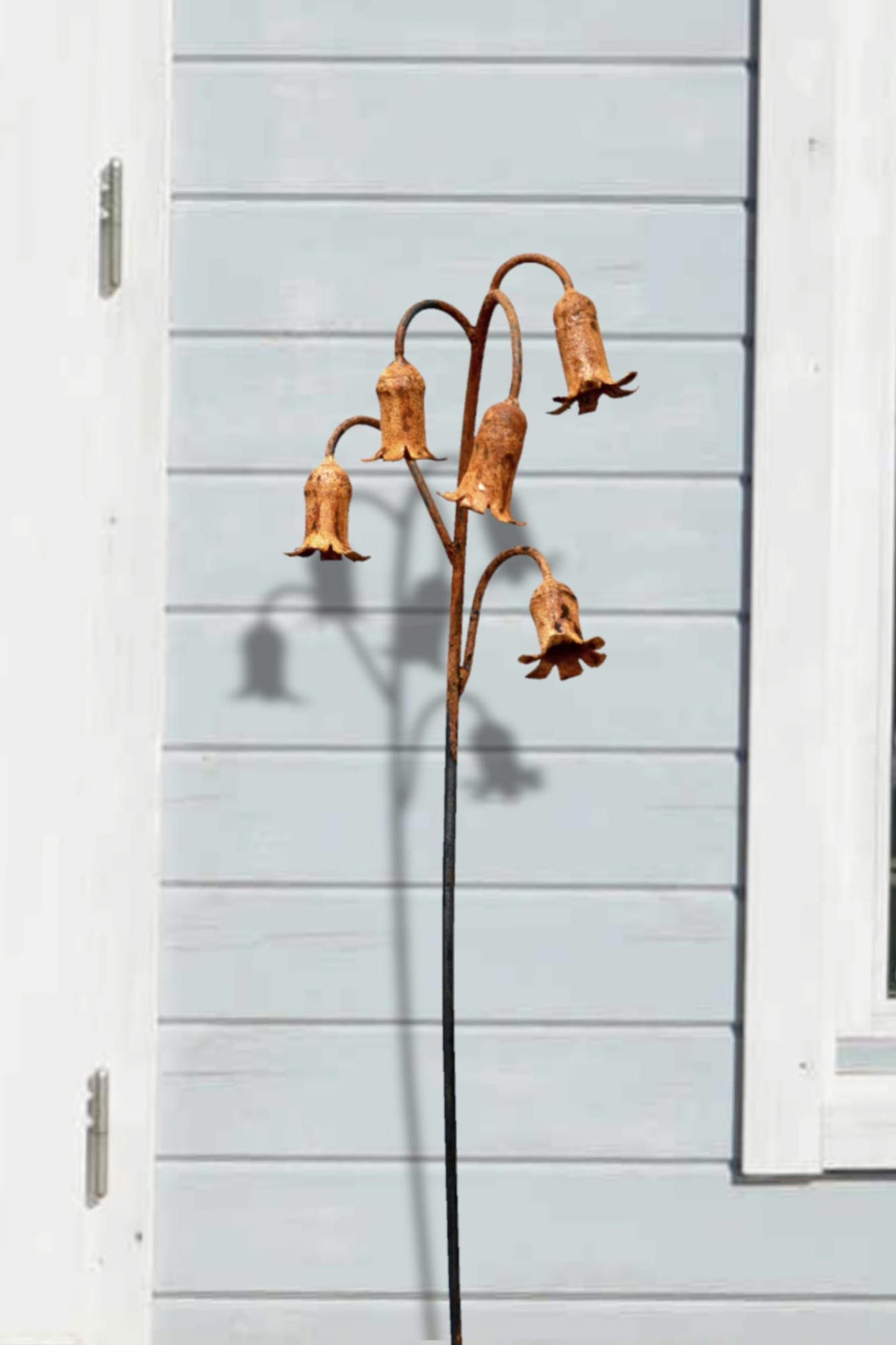Rusty metal Bluebells sculpture against a light blue wall