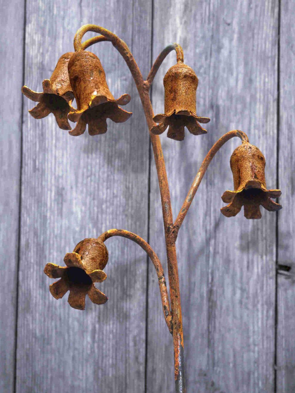 Rusty metal Bluebells sculpture against a wooden background