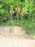 Rusty metal Daffodil sculptures against a green leafy background
