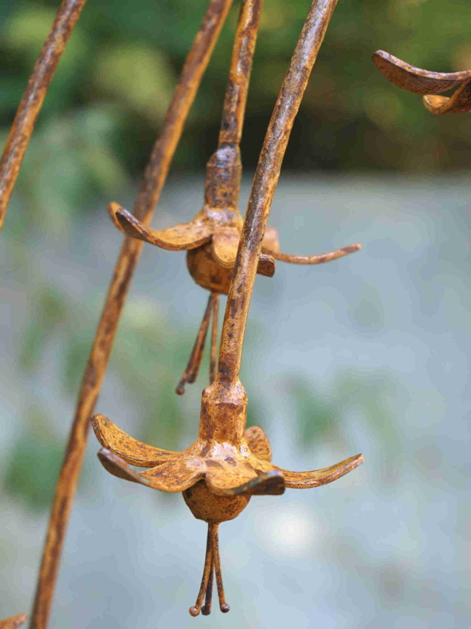 Close up image of rusty metal fuchsia flower showing the mottled patina finish