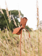 Rusty metal Iris flower sculpture in a field of tall grass