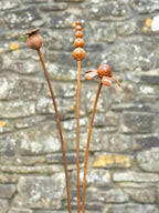 Rusty metal mixed flowers sculptures against a stone wall background