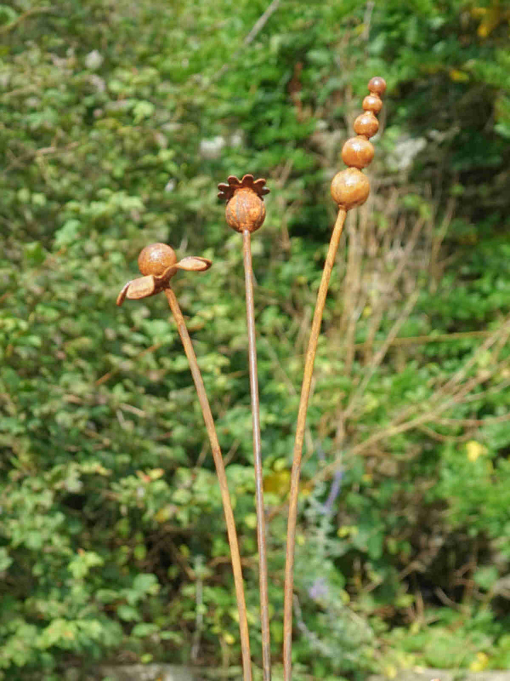 Rusty metal mixed flowers sculptures against a blurred green background