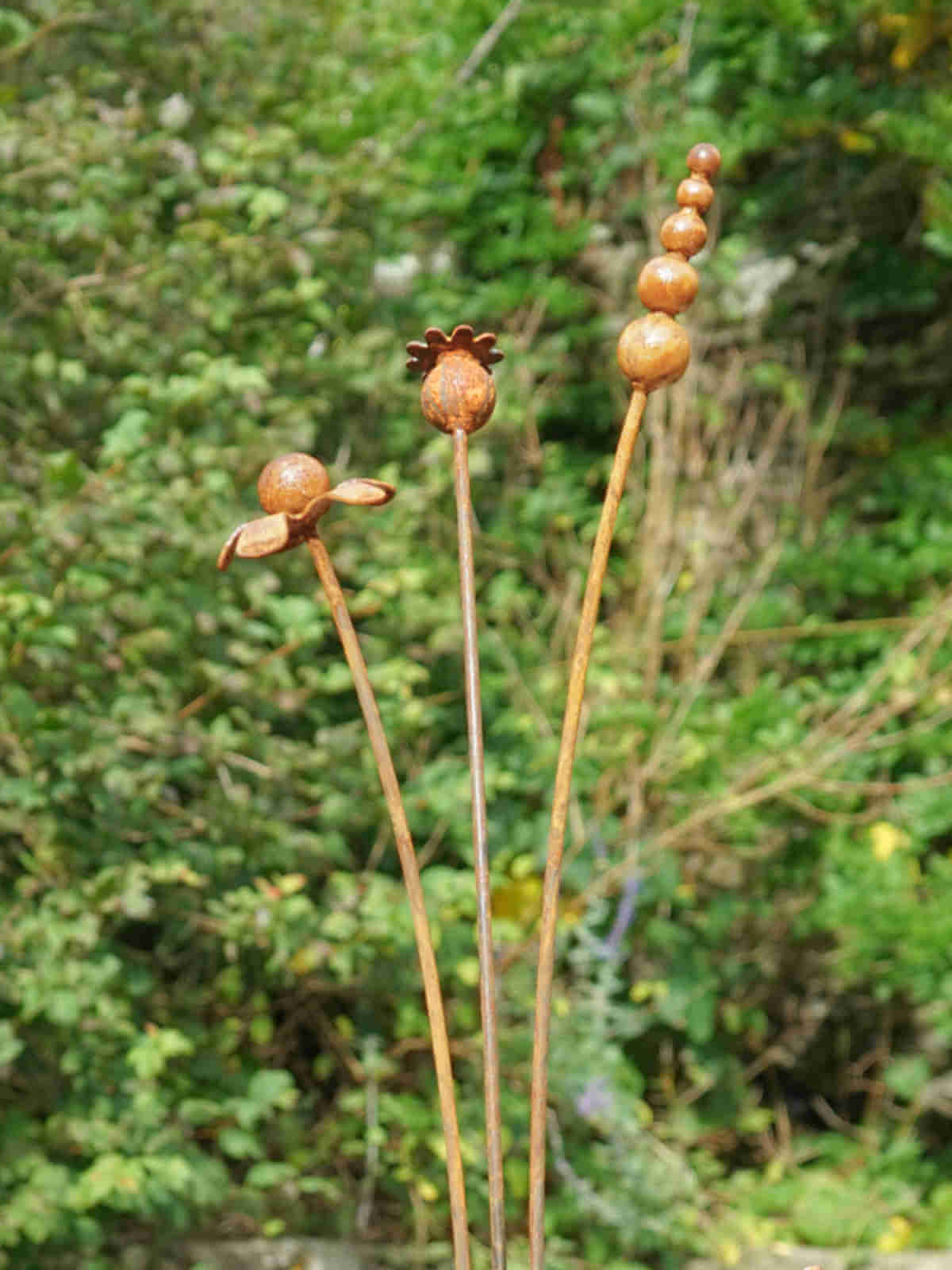 Rusty metal mixed flowers sculptures against a blurred green background