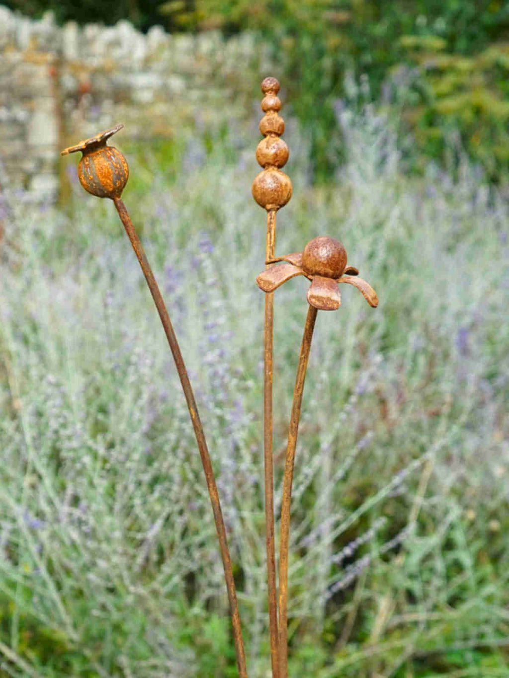 Rusty metal mixed flowers sculptures in a garden setting with lavender