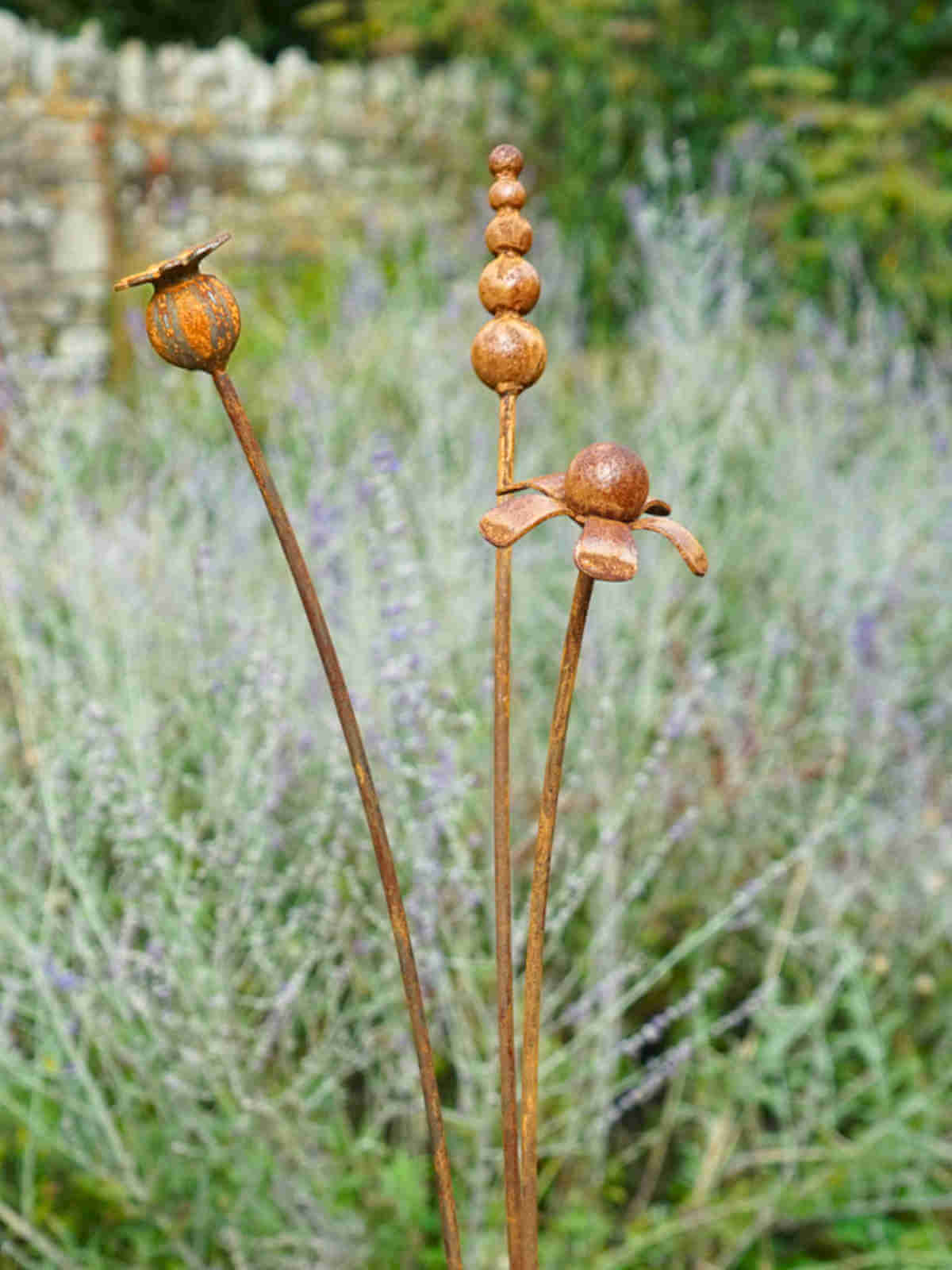 Rusty metal mixed flowers sculptures in a garden setting with lavender