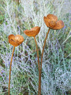 Rusty metal Poppy sculptures against a blurred natural background of blue spires