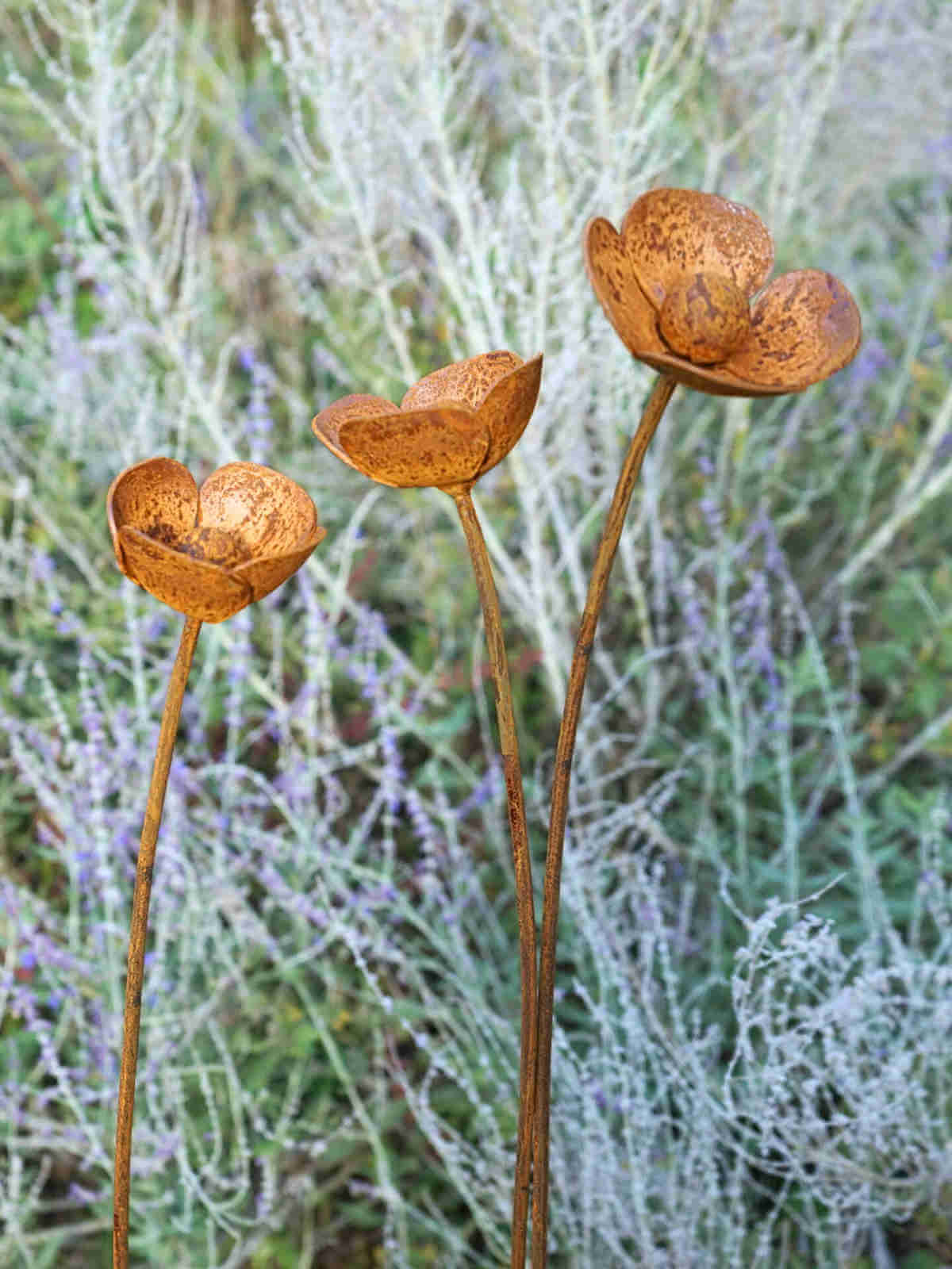 Rusty metal Poppy sculptures against a blurred natural background of blue spires