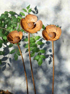 Rusty metal Poppy sculptures against a blurred natural background