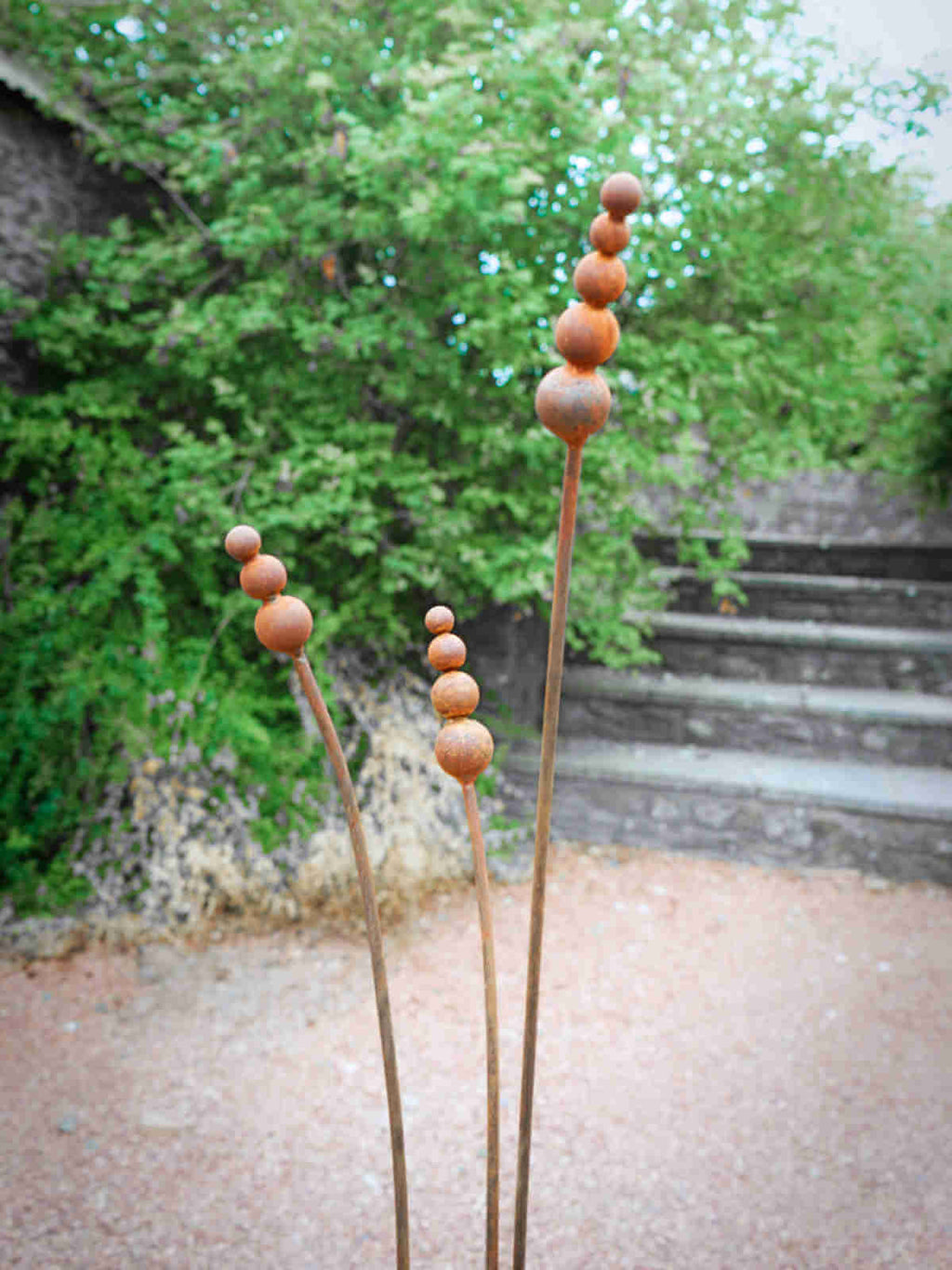 Rusty metal reed garden sculptures in a garden setting
