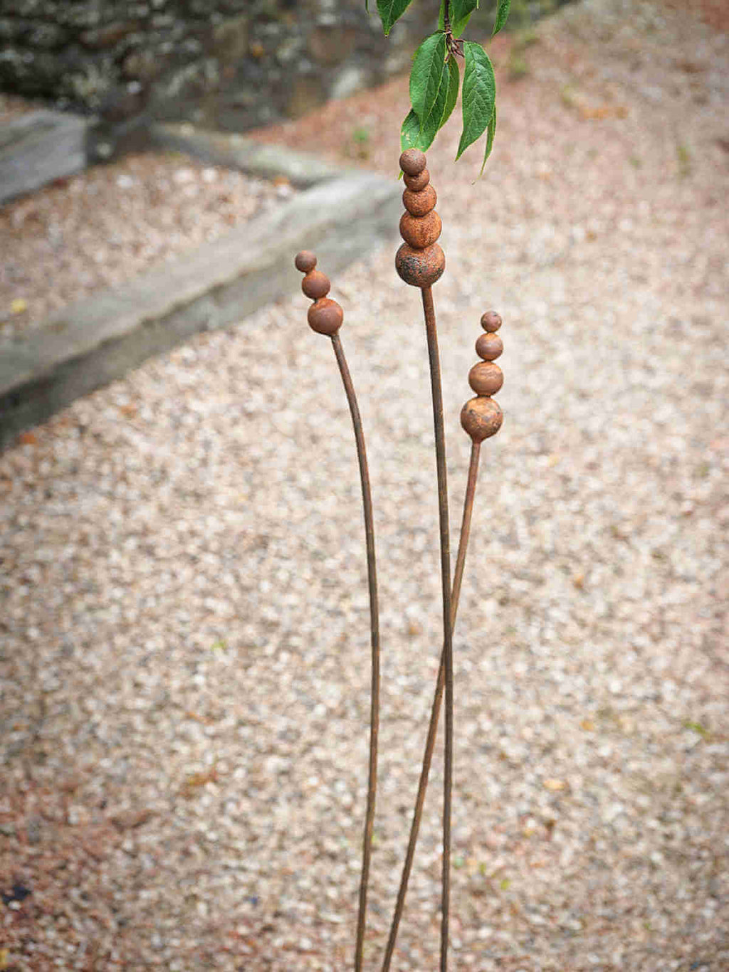 Rusty metal reed garden sculptures on a textured ground background