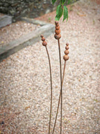 Rusty metal reed garden sculptures on a textured ground background