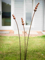 Rusty metal reed garden sculptures on a grassy lawn.