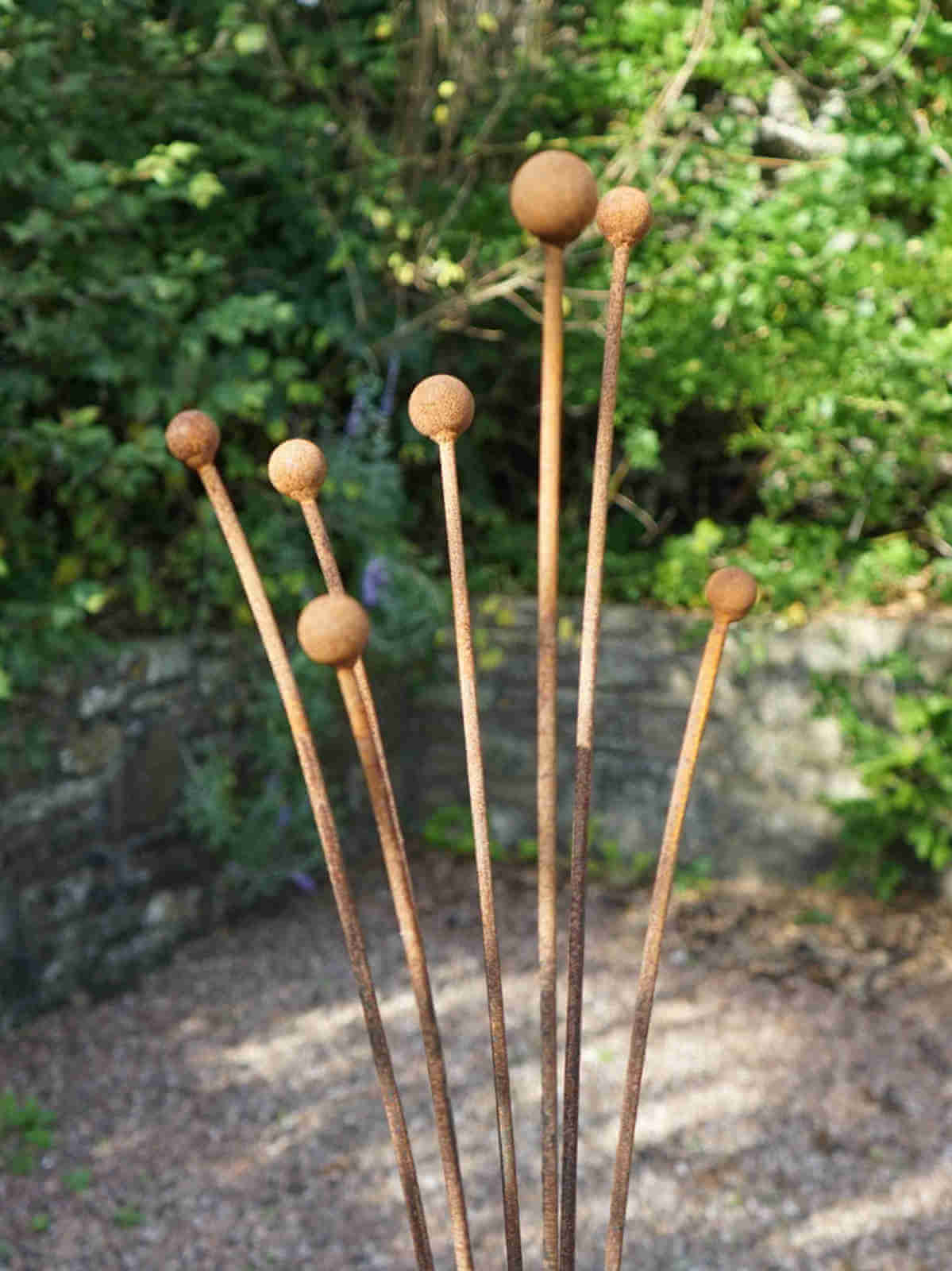 Rusty metal Seed Head garden sculpture with spherical ends against a natural background