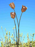 Rusty metal tulip sculptures against a clear blue sky