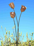 Rusty metal tulip sculptures against a clear blue sky