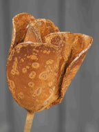 Close up image of a metal tulip flower sculpture showing the rusty patina finish